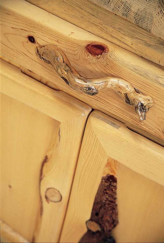 During his sojourns in the woods, Tom gathered tree roots misshapen by growing through rock cracks. This collection turned out to be the perfect hardware for the couple’s cabinets—another tribute to the land that adds texture and depth to their home. Tom had a picture in his mind of exactly the twig he wanted to use as a handle for the refrigerator—and when he took a walk in the woods near the house, nature delivered. To make the handles, Tom trimmed the edges to make them flat, then glued the roots into place on the doors. When replacing a refrigerator handle, you must utilize the same screw holes for the new handle as used for the old. Otherwise, you will create holes in the insulation of the refrigerator door that make it less efficient.